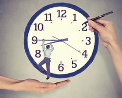 Business man trying to stop time. Man hanging on clock arrow isolated on gray office wall background. Time pressure passing past concept Business man trying to stop time. Man hanging on clock arrow isolated on gray office wall background. Time pressure passing past concept